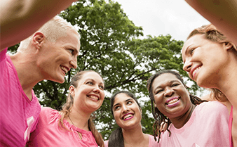A group of women in a circle supporting each other and smiling.